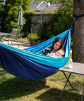 Woman with baby relaxing in Single Portable Parachute Nylon Hammock For Outdoor Adventure, tied to a tree, in backyard setting.