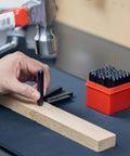 Hand holding a punch from a Number And Letter Punch Set With Heat Treated Steel Punches For Imprinting And Arts And Crafts For Hobbyists One Quarter Inch Shaft 36 Piece Stamp Kit For Beginners