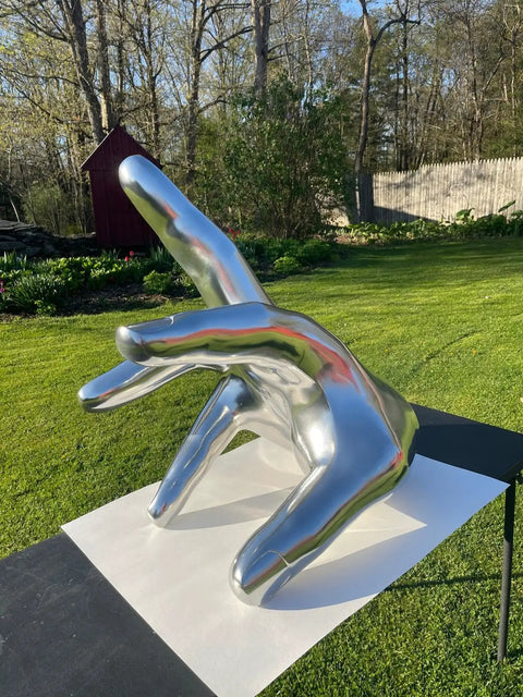 Rad Chrome Paint Pint Kit Featuring 2K Basecoat And 1K Topcoat delivers a shiny chrome hand sculpture in a garden setting.