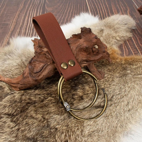 Solid leather strap with brass ring on a fur background, part of Snag This Solid Leather Waist Bag And Fanny Pack With Durable Adjustable Belt Strap Badass Steampunk Style Ideal For Festival Cosplay And Mobile Device Storage.