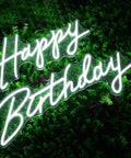 Dimmable LED Neon Birthday Sign 23 Inch Wall Backdrop Light, "Happy Birthday" glowing on a green leafy background, USB powered