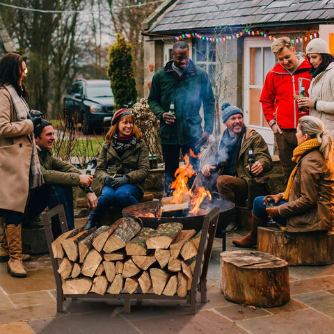 34 Inch Outdoor Indoor Firewood Rack With Bronze Finish holding logs near fireplace at outdoor gathering, enhancing drying airflow.