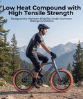 Cyclist on mountain bike with low heat compound tires in scenic mountain landscape, wearing protective gear, forest background.