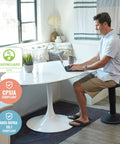 Man using SitWell Wobble Stool With Adjustable Height For Active Seating In Seafoam at a white table in a bright room.