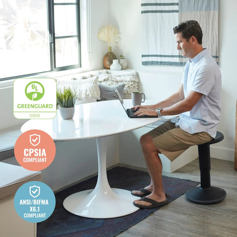 Man using SitWell Wobble Stool With Adjustable Height For Active Seating In Seafoam at a white table in a bright room.