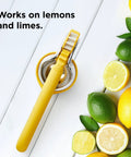 No Fuss Lemon Squeezer Citrus Juicer With Dual Gear Power Manual Hand Press next to lemons and limes on a white surface.