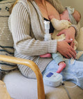 Powerhouse Rechargeable Cordless Breast Pump With Hospital Strength Suction and Dual Adjustable Settings used by mom nursing baby on couch.