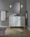 Grand Toilet Tissue Holder With Pivoting Design That Makes Replacing Toilet Paper A Breeze Easy Roll Change Modern Transitional Style That Complements Your Faucets Durable Chrome Finish For Busy Bathrooms in elegant bathroom scene with white vanity and light fixtures.