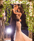 Couple embracing under arch of 33 Ft Ivy Garland With 100 LED Fairy Lights For Home Decor Living Room And Bedroom Wall Art Aesthetic Office Lighting Wedding Party Farmhouse Dorm Outdoor Garden Glow, creating a romantic ambiance.