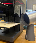 Heavy Duty Solder Fume Extractor Fan With Badass Suction And Slick Design For Desktop DIY Stations next to a workspace.