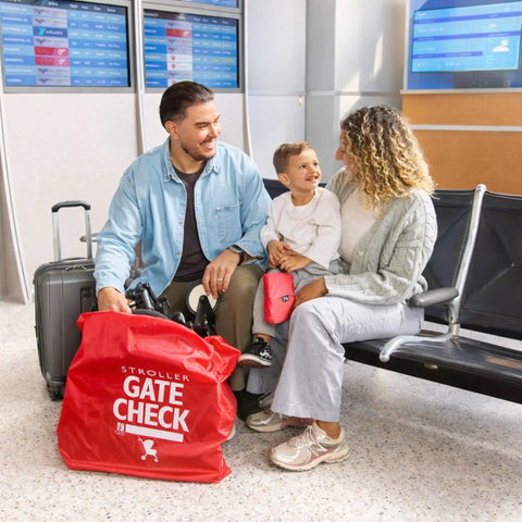 Family with a stroller and Gate Check Travel Bag For Compact Fold Strollers With Built In AirTag Holder Red at airport