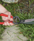 Hand using GS 6750D ClassicCUT Grass Shear Four And A Half Inch For Precise Lawn Trimming And Edging near stone border