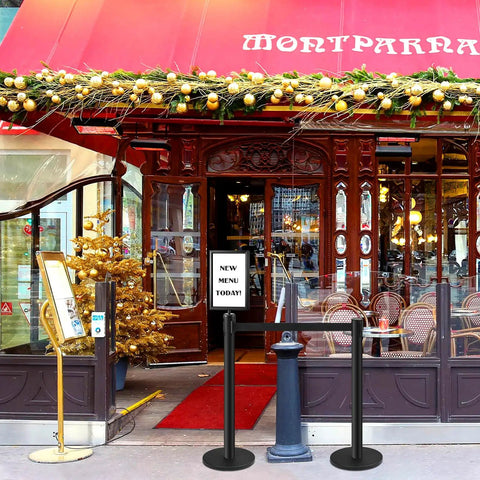 Image of a stylish restaurant entrance with Retractable Belt Stanchions 3 Pack for Crowd Control Barriers With Ropes and Poles Black Six Point Six Feet Tall Durable Stainless Steel Posts With Sign Frame Holder used for effective queue management, featuring a decorative awning and festive decorations.