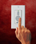 Hand operating the wall control of Aire Ceiling Fan With Full Function Wall Control For Easy Cooling, Traditional White And Gray Finish.