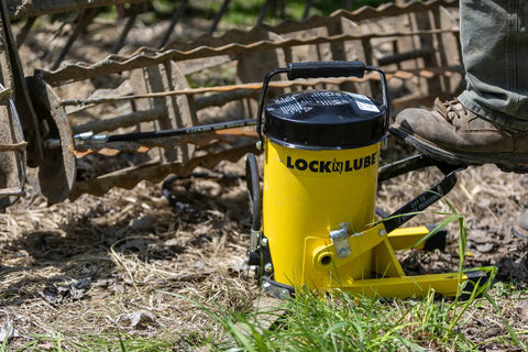 Heavy Duty Grease Gun With 10,000 Psi Output For Fast No Sweat Lubrication near machinery, foot pedal visible on grass.