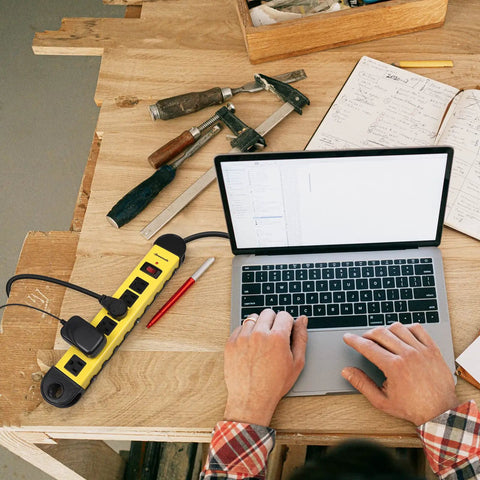 Heavy Duty 6 Outlets Power Strip Surge Protector With 15 Foot Cord UL Listed 900 Joules in use on a workbench with laptop and tools