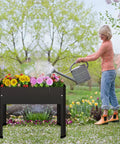 Woman watering flowers in a Raised Garden Bed All In One With Detachable Legs Elevated Metal Planter Box for Growing Herbs Vegetables Flowers Succulents and More Outdoor Garden Stand With Drainage Holes Great For Balcony Patio Deck Black.