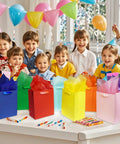 Eight Rainbow Gift Bags With Handles 8x5x10 Inches Kraft Paper Party Favor Bags With 16 Tissues, displayed at a colorful party table.