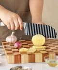 OLULU crinkle-cut knife with ribbed stainless blade and rubber handle, slicing a potato on a wooden cutting board.