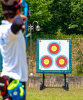 Archer aiming at 100 Pack Archery Target Paper 3 Spot Targets 17 By 17 Inches with 4 Archery Target Pins in a field