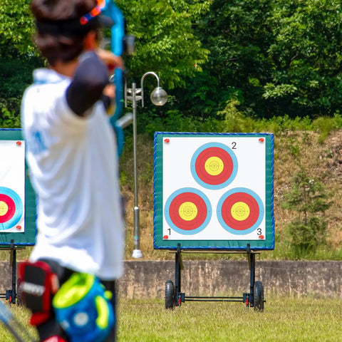 Archer aiming at 100 Pack Archery Target Paper 3 Spot Targets 17 By 17 Inches with 4 Archery Target Pins in a field