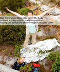 Person using an Emergency Survival Reflective Blanket For Camping And Hiking Packable Thermal Shield Multipurpose Tent And Sleeping Bag Lightweight Rescue Gear For Outdoor Adventures Silver in a forest.