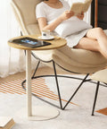Woman relaxing with book next to C Shaped Round End Table With Metal Legs For Couch, Snack Sofa Tray Or Laptop Desk in rustic oak finish.