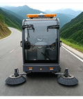Heavy Duty Industrial Floor Sweeper Machine For Warehouses And Factories with dual brushes on a road surrounded by mountains.