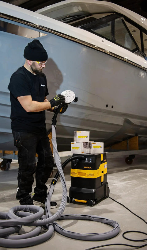 Industrial Job Site Dust Extractor Packing Thirty Liters Of Raw Suction And M Class HEPA Filtration, worker using sander in boat detailing.