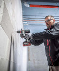 Man using Premium 18V Brushless Cordless Hammer Drill Driver featuring a beefy half inch chuck on concrete wall.