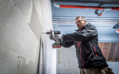 Man using Premium 18V Brushless Cordless Hammer Drill Driver featuring a beefy half inch chuck on concrete wall.