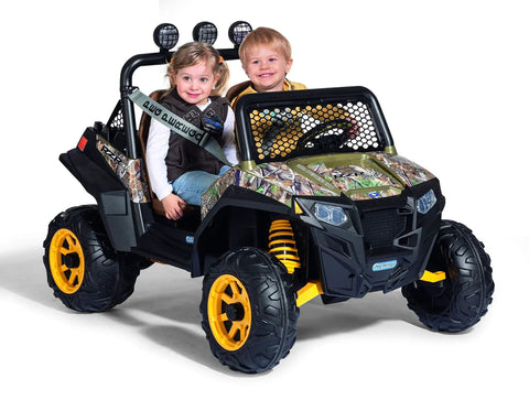Two children seated in a camo-patterned ride-on toy resembling a John Deere Gator XUV and Polaris RZR 900 model.