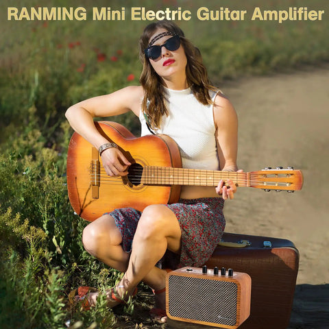 Woman sitting outdoors with a wooden acoustic guitar and 10W Mini Guitar Amp With Clean And Drive Channels beside her on a suitcase.