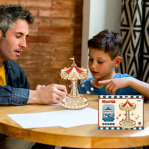 Father and son assembling 3D Wooden Puzzle Music Box Kit With Led Rotating Swing Ride on table, box shown on side.