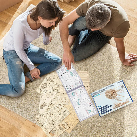 Couple assembling LED Jellyfish 3D Wooden Puzzle Kit For Adults With 355 Pieces That Swims When LED Lights Up Realistic Display Build DIY Wood Craft Toy Gift For Him And Her Cool Creative Hobby And Unique Educational Toy on carpet
