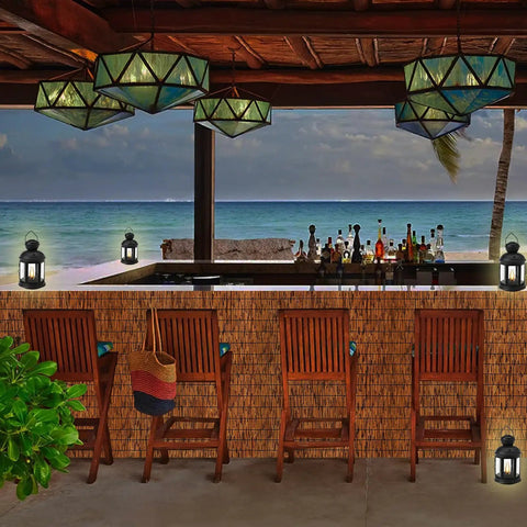 Outdoor bamboo bar with reed fencing, wooden chairs, lanterns, ocean view in background, evening ambiance