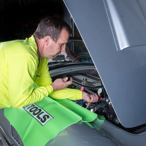 Mechanic using Cooling System Pressure Test Pump Kit For Cars And Trucks, Near Universal Leak Tester on vehicle engine