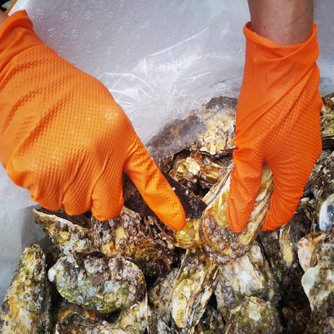 TitanFlex heavy-duty orange nitrile gloves with raised diamond texture grip gripping oyster shells