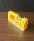 QERDIVO Spirit Levels Mini Horizontal Vertical Pockets Spirit Level with clear bubble in compact yellow design on wooden surface.
