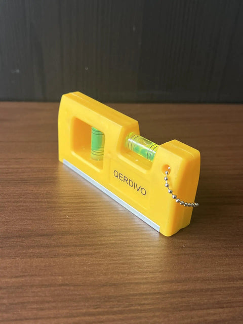 QERDIVO Spirit Levels Mini Horizontal Vertical Pockets Spirit Level with clear bubble in compact yellow design on wooden surface.