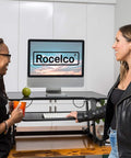 32 Inch Height Adjustable Standing Desk Converter With Slide Out Keyboard Tray and Dual Monitor Riser, two women using it in a bright office.
