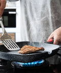 Man grilling steak on Square Indoor Grill Pan With Removable Handle For Even Heating Meat And Veggies, 11 Inch Nonstick Griddle Skillet, RV Die Cast Aluminum Stove Top Grill Pan, Detachable Handle, Oven Safe Up To 480 Degrees