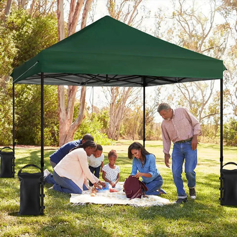Heavy Duty Sand Bags For Canopy Legs Set Of 4 add stability to a pop-up tent in a park setting, people gathered under a green canopy.