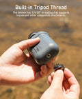 Hands holding Nestout Rugged 15000mAh Power Bank showing built-in tripod thread for outdoor adventures.
