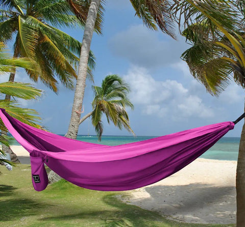 Double Camping Hammock With Ropes For Two People, Ultra Lightweight Portable Gear, 210T Nylon Parachute Fabric, Fuchsia Pink on a beach.