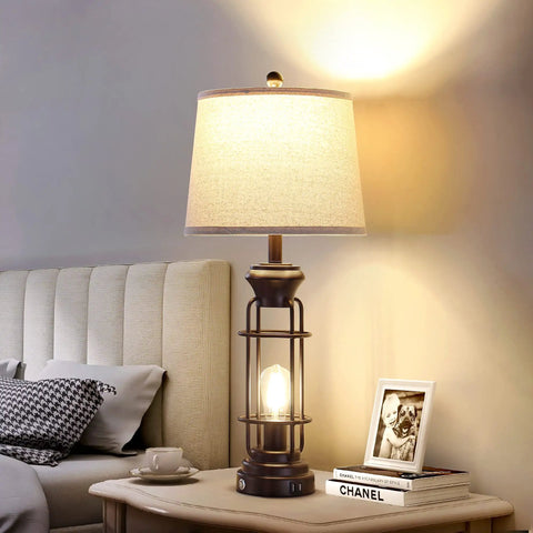 Set Of 2 Farmhouse Tall Table Lamps For Living Room And Bedroom, Oil Rubbed Bronze Finish With White Oatmeal Linen Shade, Dual USB Charging Ports, Bulbs Included, Sturdy Metal Construction, placed beside a bed on a side table.