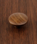 Round walnut wood cabinet knob on surface, part of 10 Pack Round Walnut Wood Cabinet Knobs With Screws 1.57 Inch Diameter Ideal For Cabinets Dresser