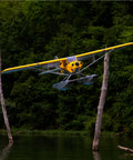 Carbon Cub 15cc ARF Ready To Fly RC Plane With Laser Cut All Wood Construction in flight over water with backdrop of trees.