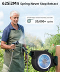 Man using Retractable Garden Hose Reel 100 Feet One Half Inch With Pro Metal Shaft in garden, wall-mounted with hose extended.