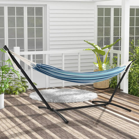 Two Person Outdoor Hammock With Adjustable Metal Stand For Patio Or Garden set up on a wooden deck, blue fabric, space-saving design.